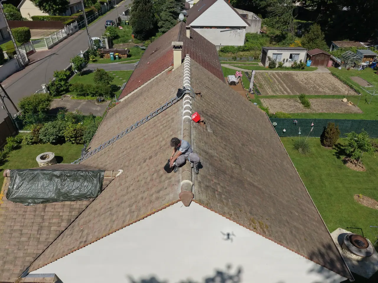 Couvreur posant des tuiles sur une toiture à Septeuil